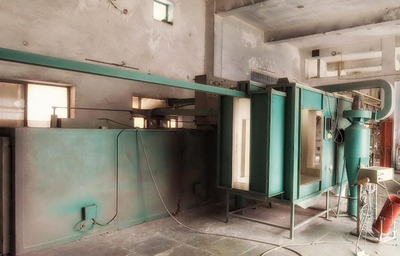 Powder coating application with electrostatic spray gun applying coloured powder onto aluminium architectural profiles in a spray booth