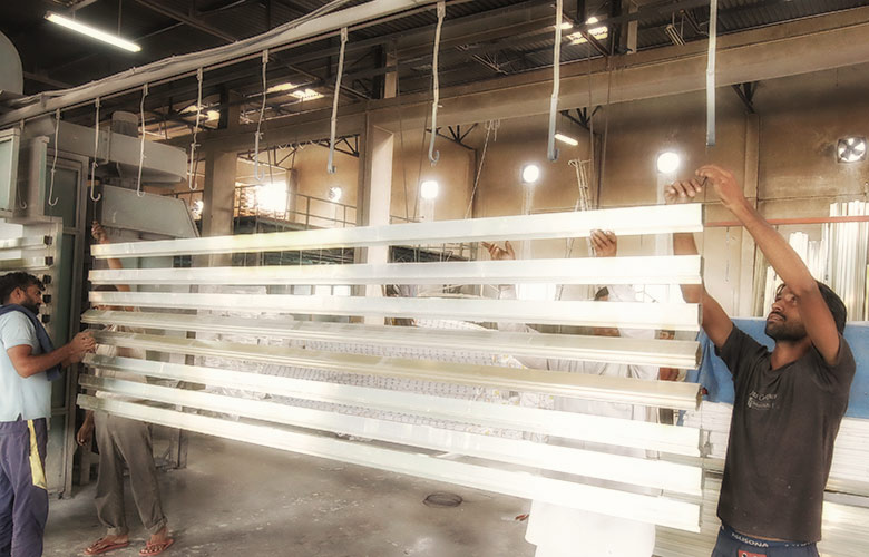 Aluminium profiles being jigged onto the long conveyor system at Radiant Anodisers Behror for coating processing
